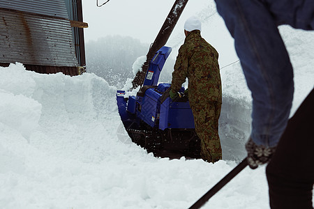推着除雪机处理积雪的工人图片