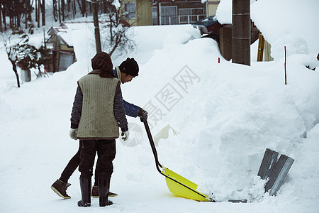 使用雪铲除雪的男性图片