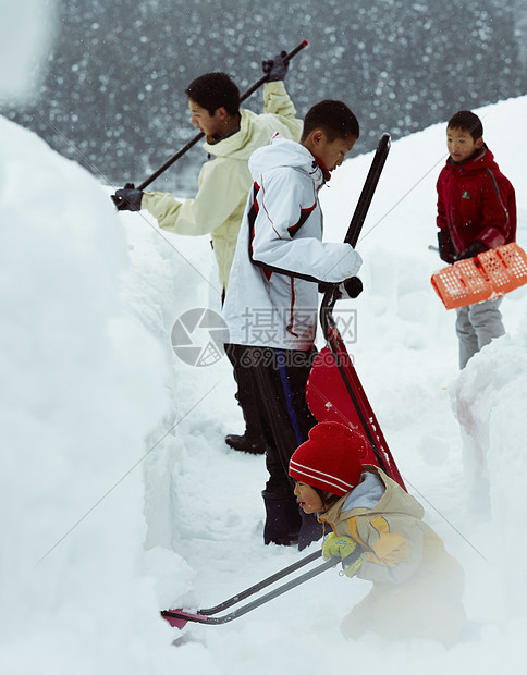 雪地里使用雪铲除雪的孩子们图片