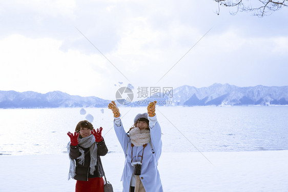 冬季旅程雪景区湖畔玩耍的少女图片