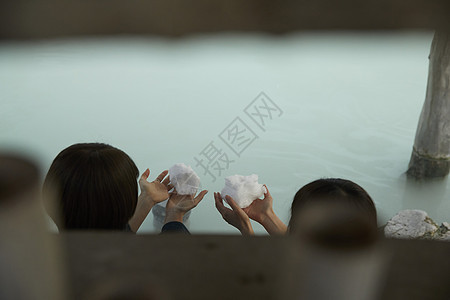 冬季雪天户外泡温泉捏雪球的少女图片