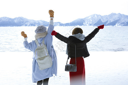 冬天两位女性游客在雪地里漫步背影图片