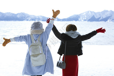 冬天两位女性游客在雪地里漫步背影图片