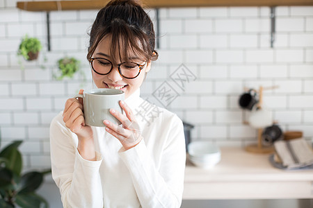 厨房里捧着杯子的年轻居家女性图片