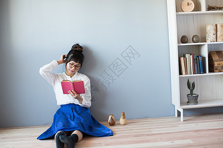 坐在地上阅读书籍的女性图片