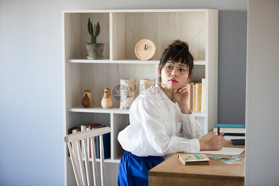 戴眼镜的女孩拿着笔在书房思考图片