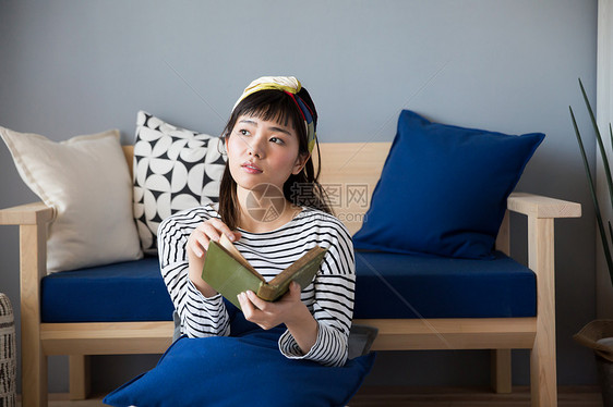 坐在客厅休息看书的女青年图片