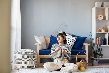 客厅地毯上编织毛线的女青年图片