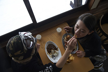 滑雪场餐厅享有午餐喂食的年轻夫妇图片