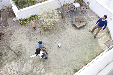 父亲和两个小孩在庭院里踢球图片