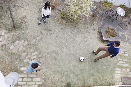 父亲和两个小孩在庭院里踢球图片