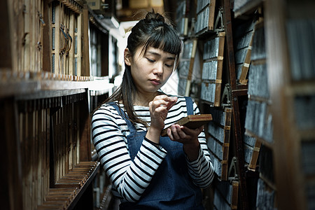 年轻女人在活版印刷工艺品仓库图片