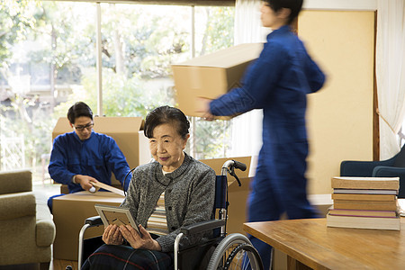 坐轮椅的年迈妇女在搬家时看相框图片