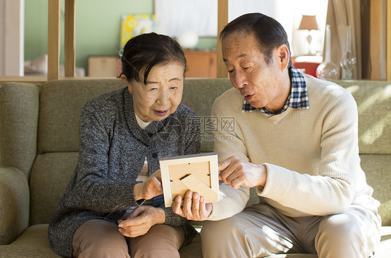 老年夫妇在沙发上看相框图片