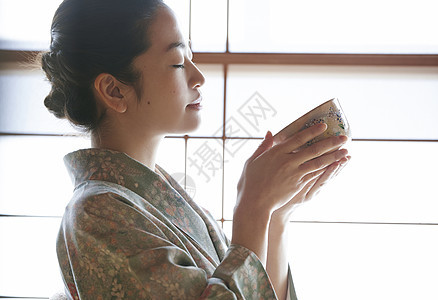 日式服装成就室内享受茶道的妇女图片