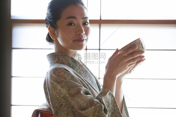 穿着日式服装捧着茶碗的年轻女性图片