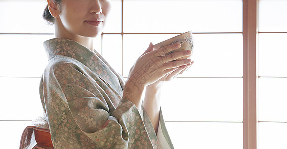 穿着日式服装捧着茶碗的年轻女性背景图片