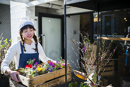 花店门口的女老板打理花店图片