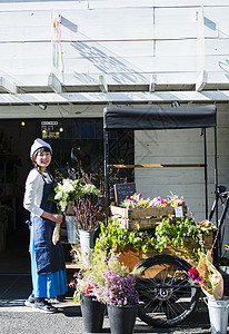 花店门口的女老板打理花店图片