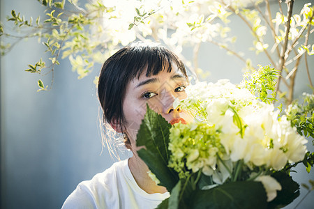  阳光下抱着花的女性图片