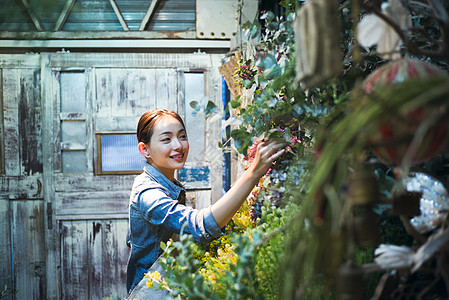 插花艺术快乐的植物的年轻工作在花店的妇女背景