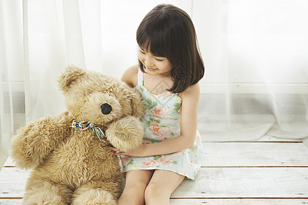 坐在地板上抱着泰迪熊的小女孩图片