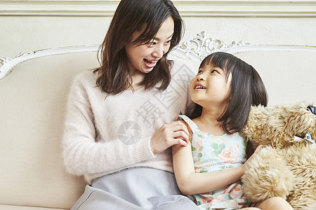 母亲和女儿抱着娃娃坐一起说笑图片