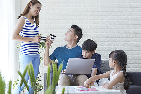 客厅中陪伴儿女学习的父母背景图片