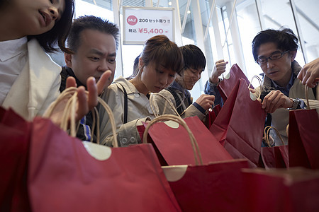 人们看百货商店出售打折商品图片