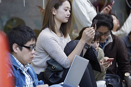 人群在商店外有序排队玩手机办公图片