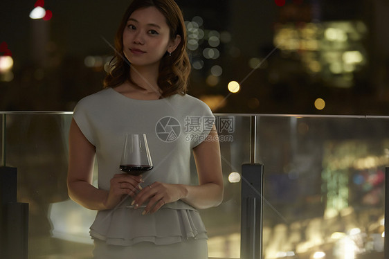 夜景漂亮女人在露台上喝酒图片