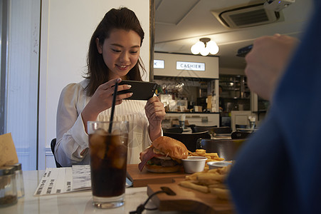 汉堡店内拍摄美食的女生图片素材