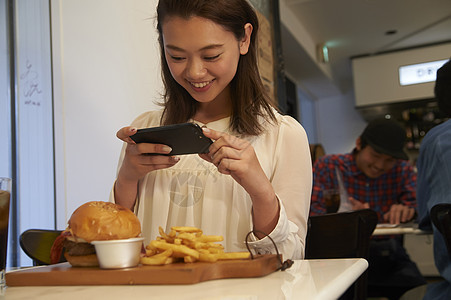 一个女人在汉堡店用餐拍照图片