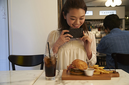 一个女人在汉堡店用餐拍照图片