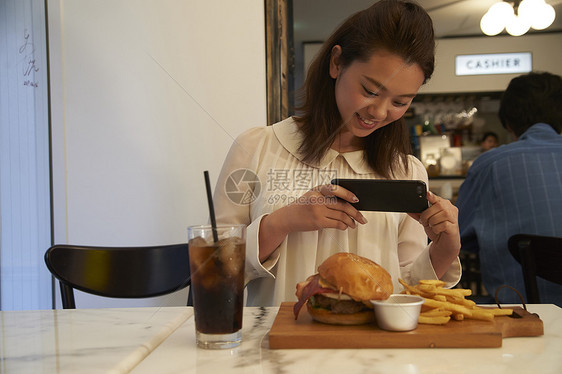 一个女人在汉堡店用餐拍照图片