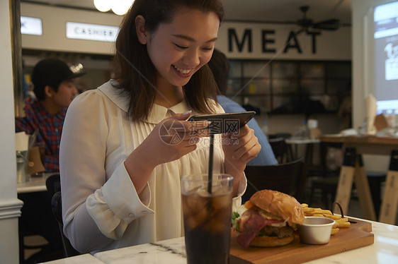 一个女人在汉堡店用餐拍照图片