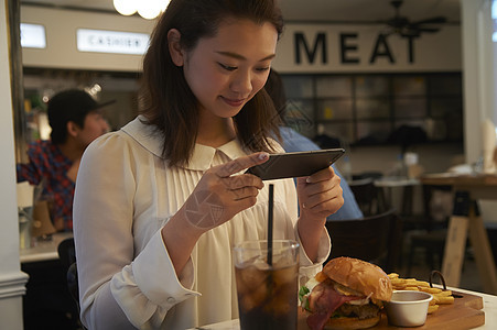 一个女人在汉堡店用餐拍照图片