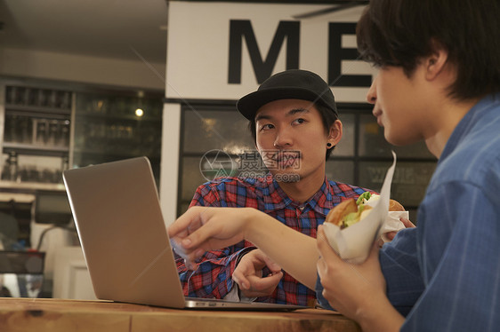 午餐时间看着笔记本开会的青年男性图片