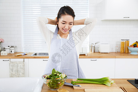 在开放厨房里切菜的年轻女性图片