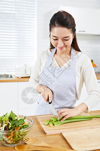 在开放厨房里切菜的年轻女性图片