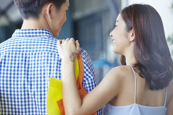 拎着购物袋购物的年轻夫妇背影图片