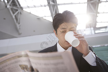 喝着水看着报纸的年轻男性图片