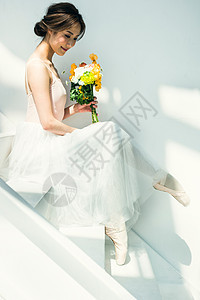 拿着花束做在台阶上的芭蕾舞女演员图片