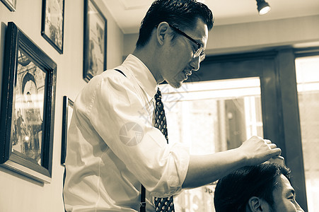 穿衬衫系领带的文艺理发师给顾客理发图片