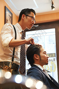 穿衬衫系领带的文艺理发师给顾客理发图片
