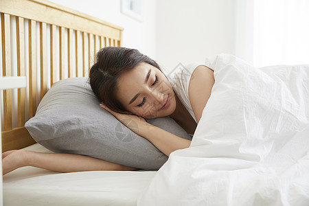 床上闭眼熟睡的年轻女子的居家生活图片