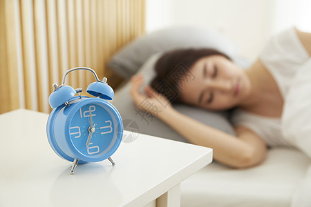 年轻女性床头柜的蓝色闹钟图片