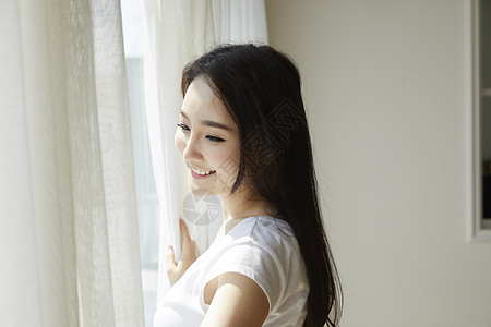 窗户旁微笑的年轻女性图片