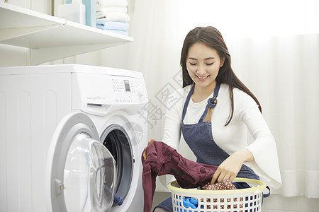 将换洗衣物放入洗衣机的年轻女性图片