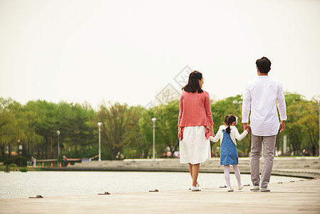 河岸边散步的一家人背影背景图片